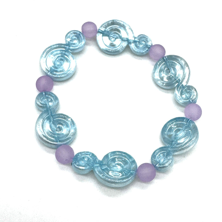 A beaded stretch bracelet featuring light blue translucent spiral-shaped beads and small matte lavender-purple round beads, displayed on a clean white background.