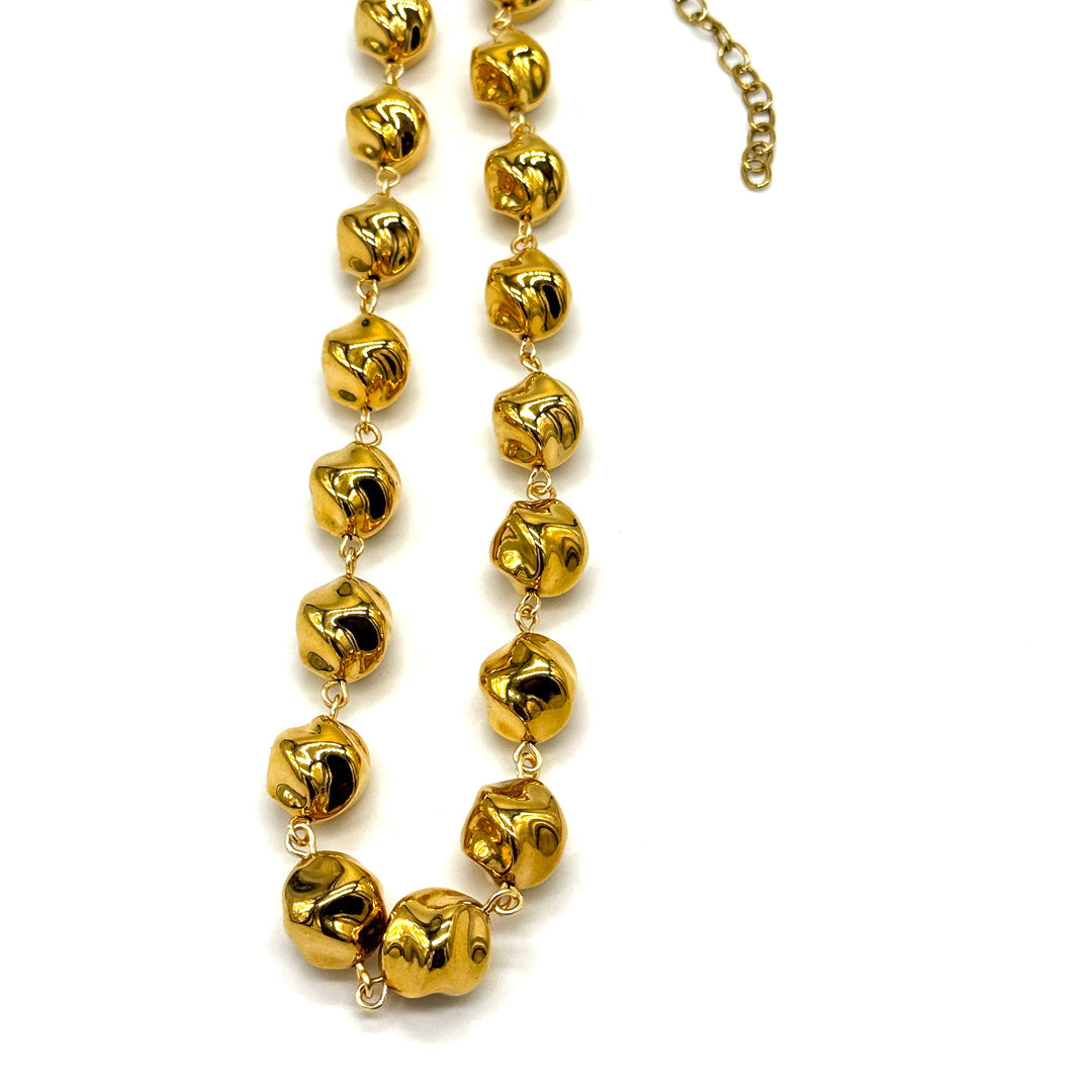 A gold-toned beaded necklace with irregular, textured spherical beads connected by delicate chains, shown on a plain white background.