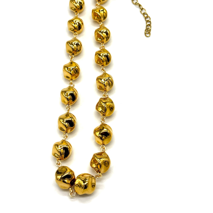 A gold-toned beaded necklace with irregular, textured spherical beads connected by delicate chains, shown on a plain white background.