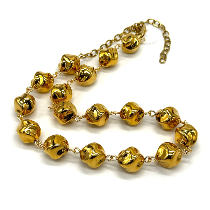 A gold-toned beaded necklace featuring textured, irregularly shaped beads connected by delicate chains, displayed on a clean white background.