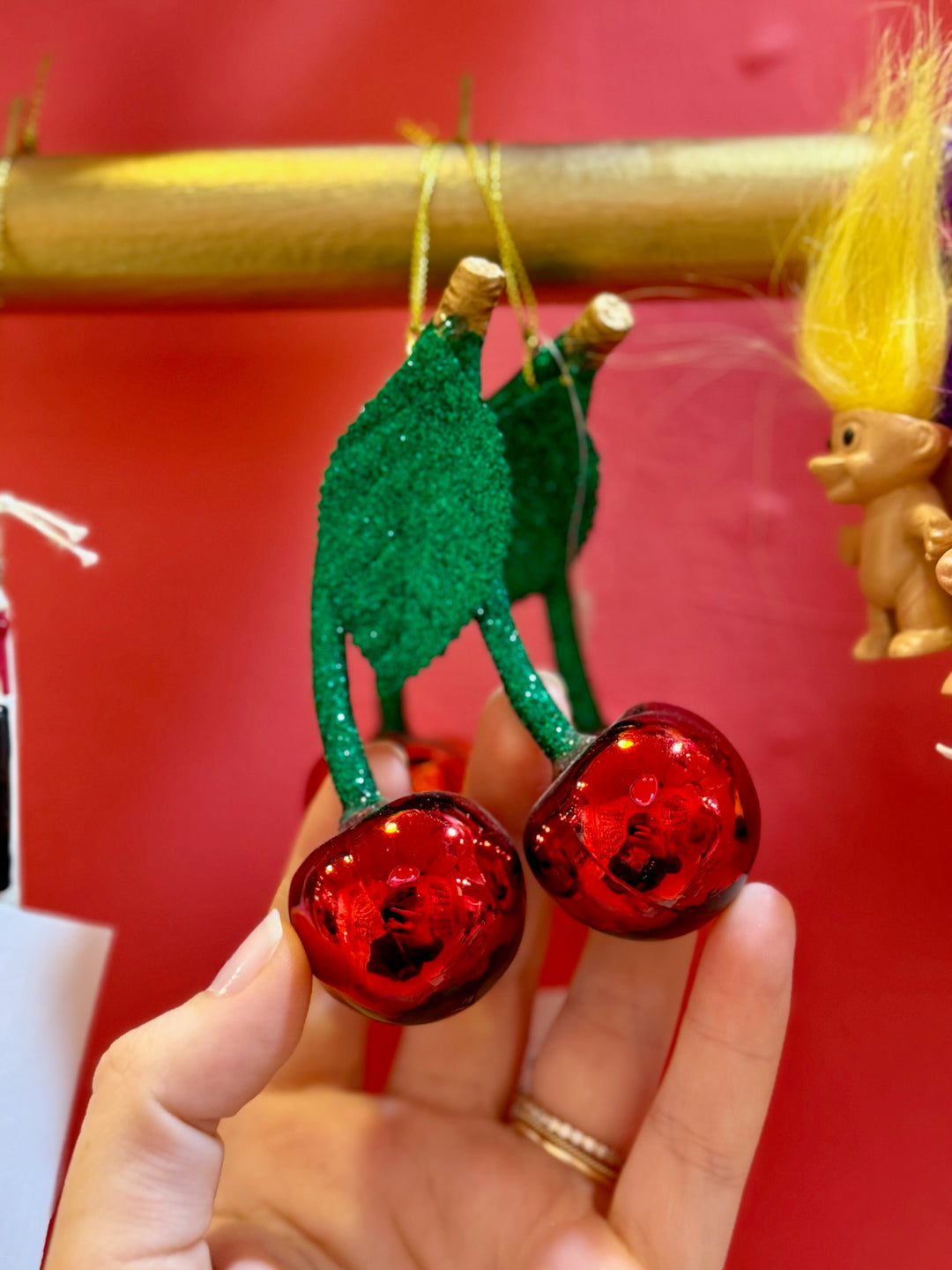 Hand holding a decorative green and red item against a red background