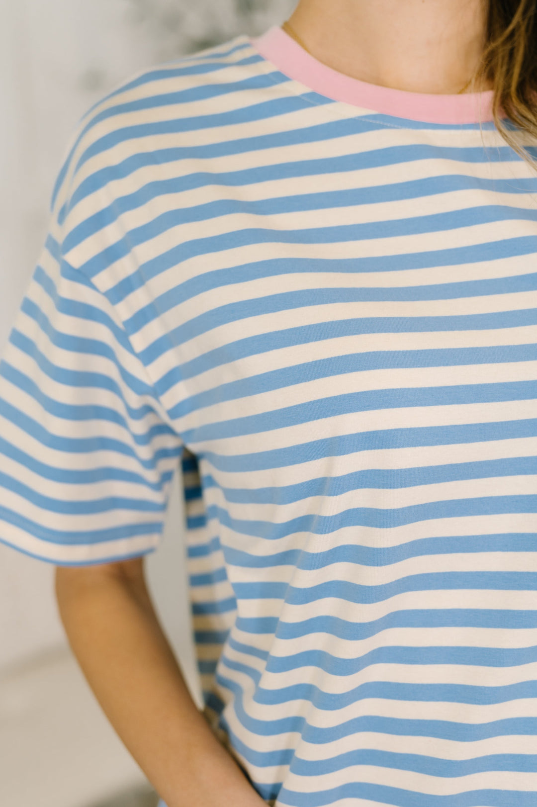 Close-up of a blue and white striped short-sleeve top with pink crew neckline