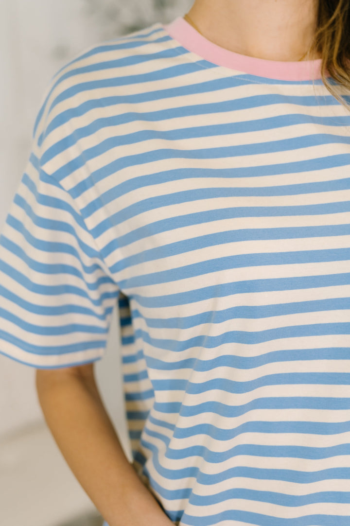 Close-up of a blue and white striped short-sleeve top with pink crew neckline