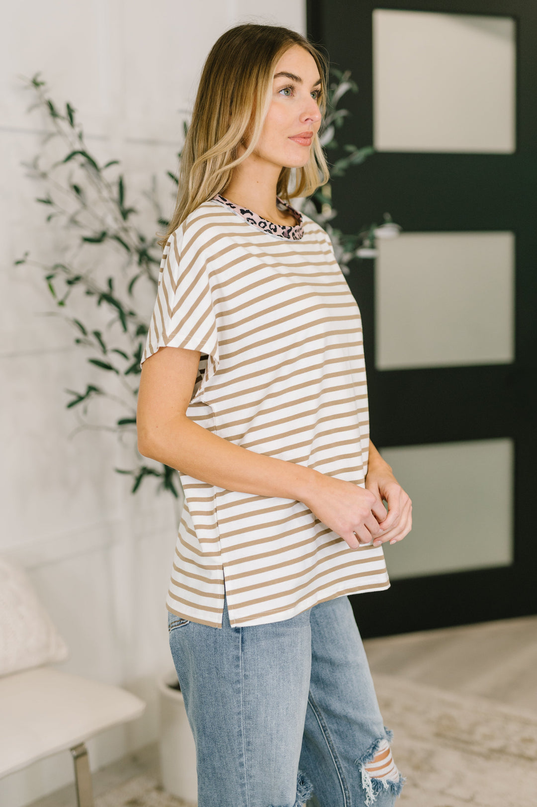 Side view of white and tan striped oversized tee showing relaxed fit, dropped shoulders, and side slit hem, styled with light wash jeans.