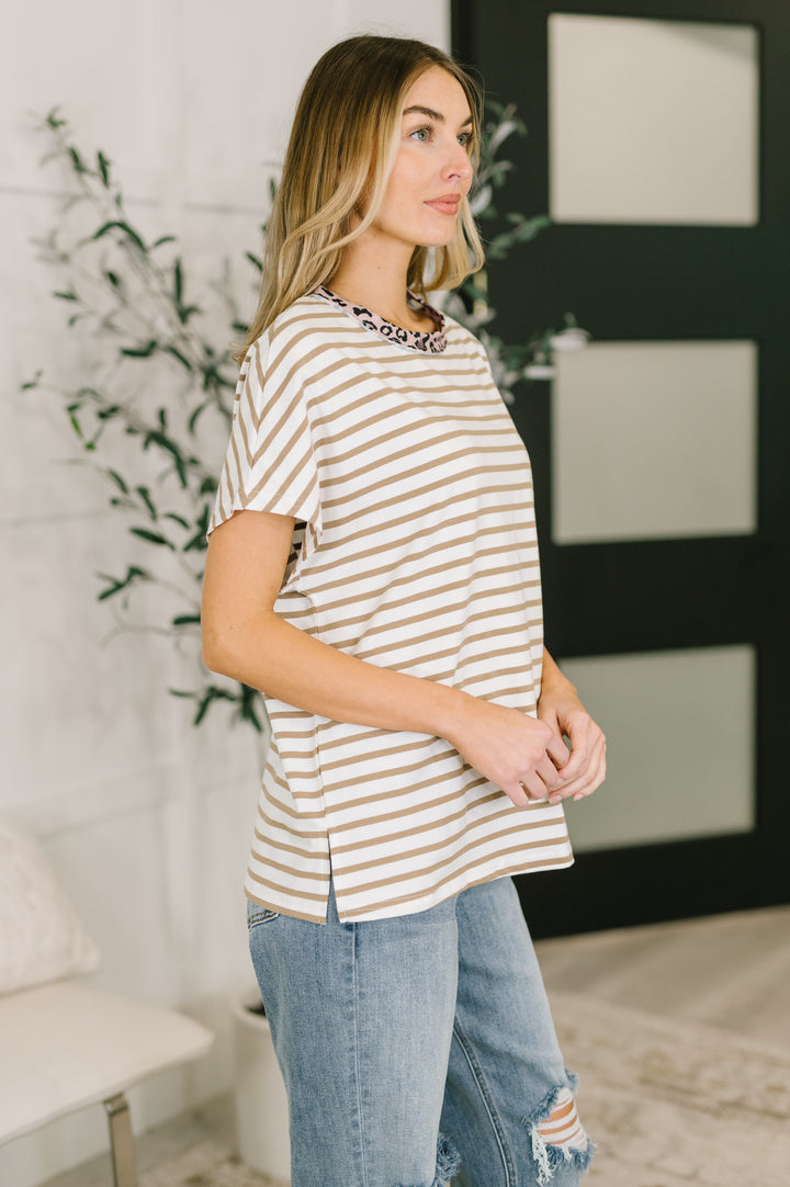 Side view of white and tan striped oversized tee showing relaxed fit, dropped shoulders, and side slit hem, styled with light wash jeans.