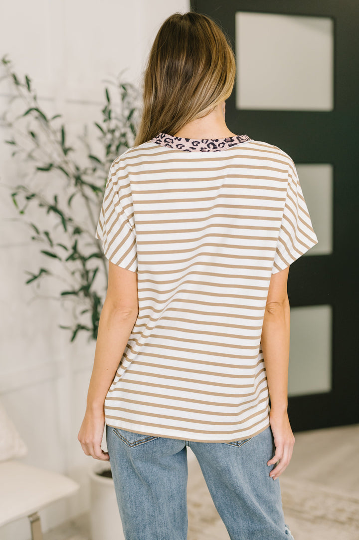 Back view of white and tan striped oversized tee showing pink leopard print neckline trim and relaxed silhouette, styled with light wash jeans.