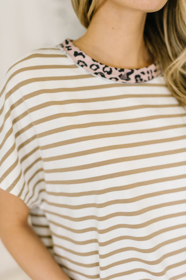 Close-up of white and tan striped oversized tee showing pink leopard print crew neckline trim detail.

