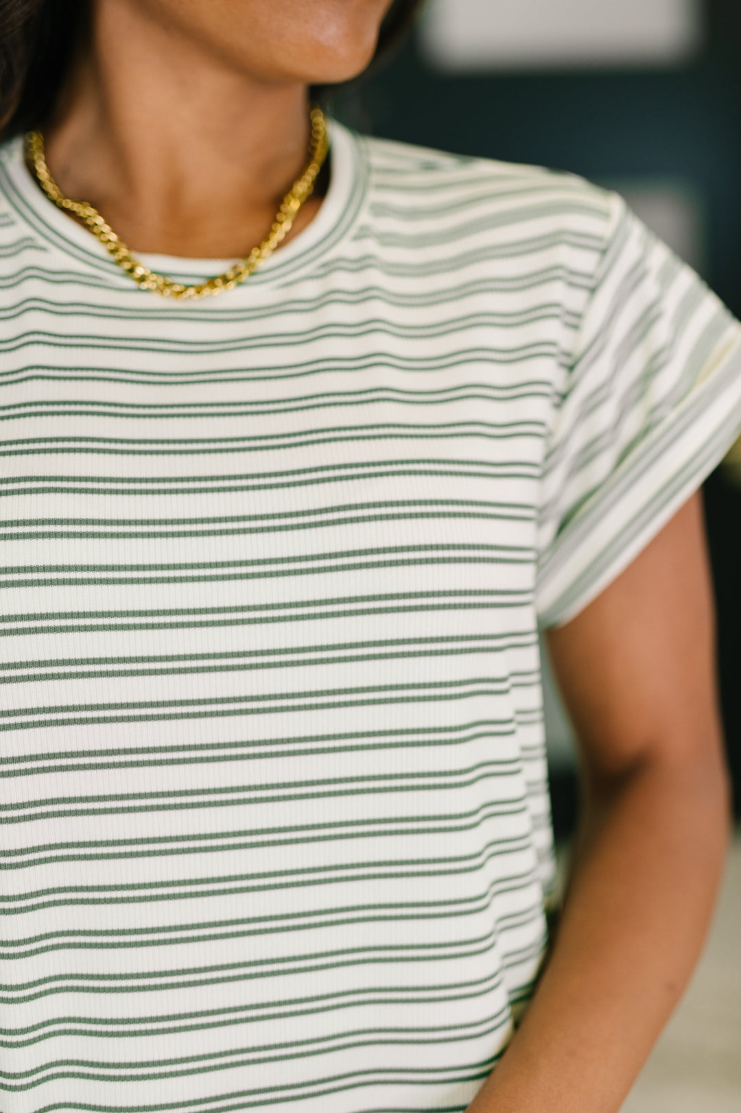 Close-up of the white and olive green striped short-sleeve maxi dress neckline with a gold chunky chain necklace

