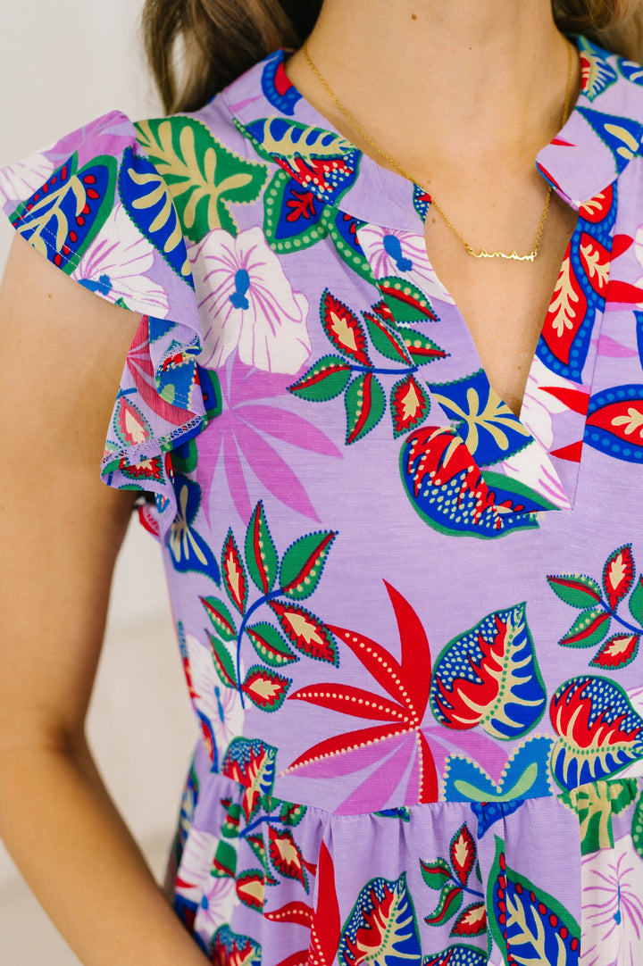 Close-up of a lavender tropical floral mini dress with flutter sleeves and V-neckline