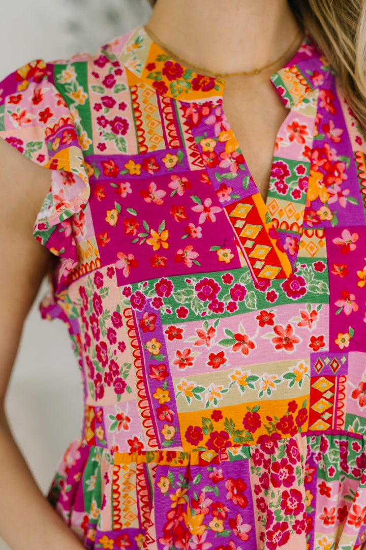 Close-up of a bright pink patchwork floral mini dress with flutter sleeves and V-neckline