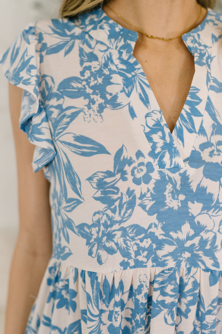 Close-up of a white and blue floral mini dress with flutter sleeves and V-neckline