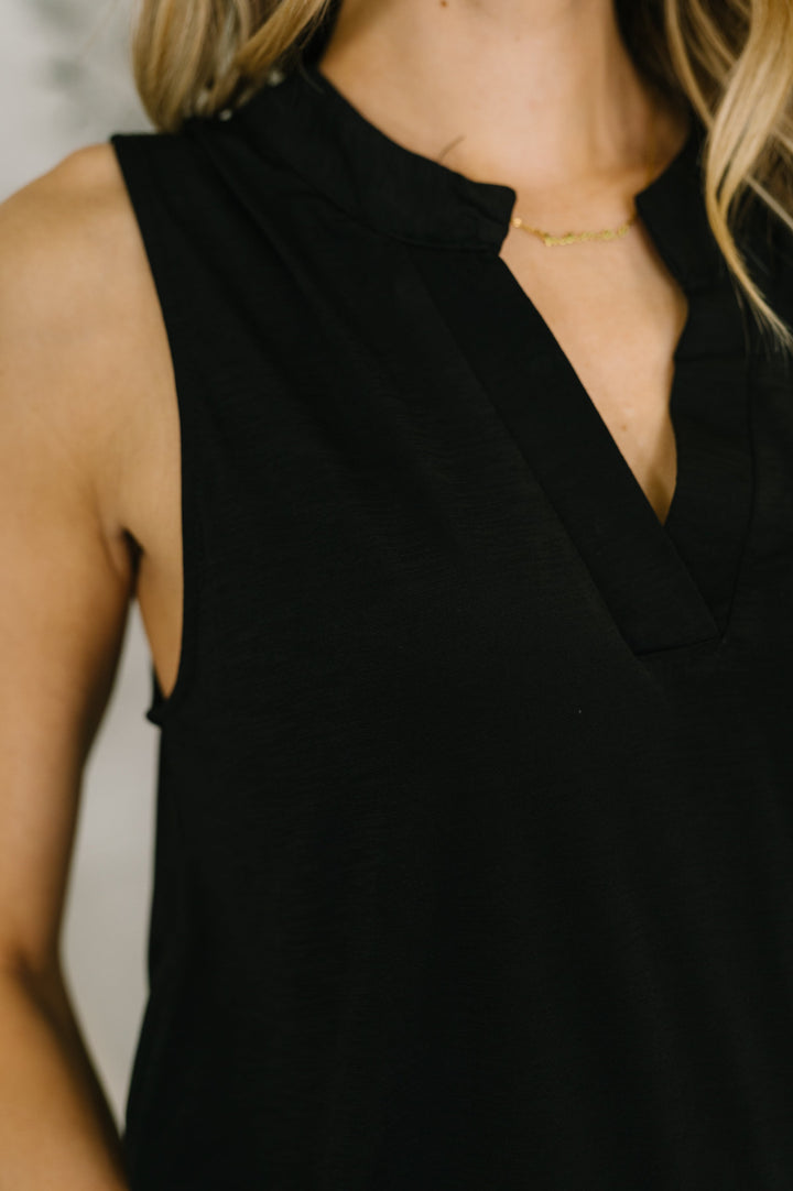 Close-up of the black split-neck neckline with subtle notch detail and a delicate gold necklace.