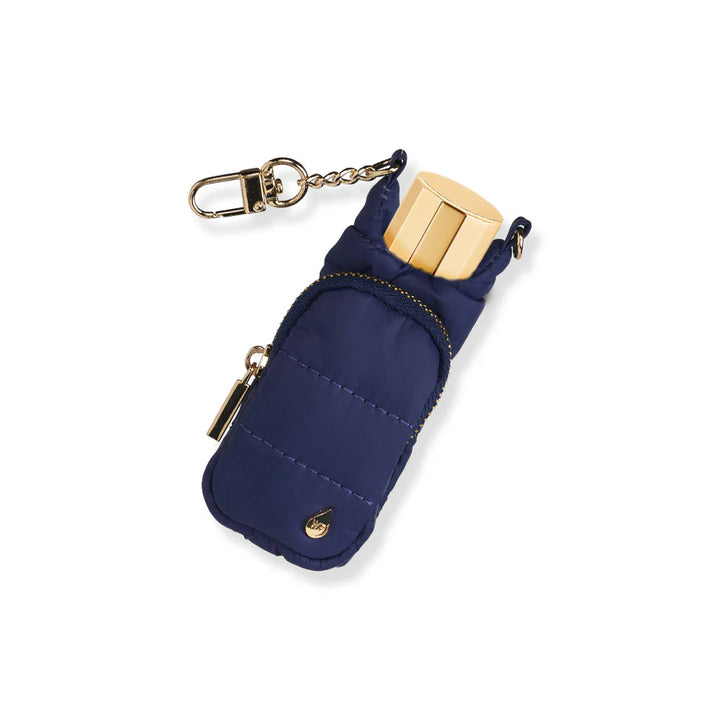 Navy blue quilted puffer lip balm keychain holder with gold lip balm tube inserted, gold zipper pocket, and gold swivel clip chain, on a white background.