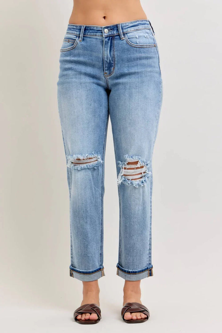 Front view of light wash distressed straight-leg jeans with frayed double knee cutouts and cuffed hem in plus size paired with brown woven slide sandals