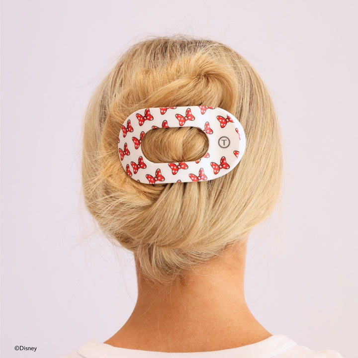 Disney x Teleties Minnie Mouse large flat round hair clip in white with allover red polka dot bow print securing a twisted low chignon on blonde hair against lavender background