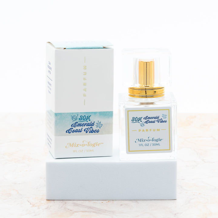 Mixologie Parfum in 30A Emerald Coast Vibes, 1 fl oz, clear square glass spray bottle with gold cap and light blue beach-themed box