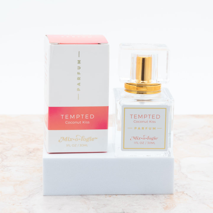 Mixologie Parfum in Tempted Coconut Kiss, 1 fl oz, clear square glass spray bottle with gold cap and coral pink box
