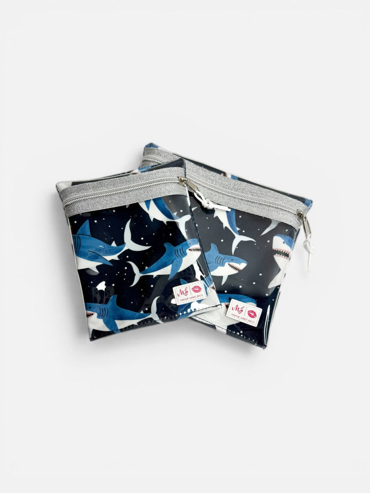Makeup Junkie Bags set of two small clear zip pouches in navy shark print with silver glitter zippers on light gray background