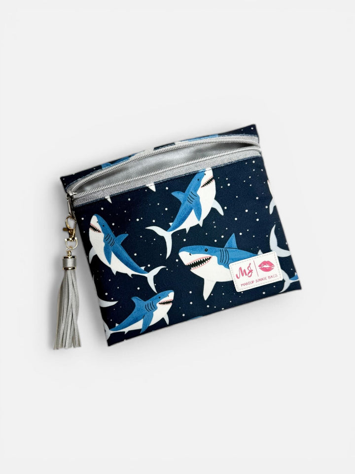 Makeup Junkie Bags medium fabric zip clutch in navy shark print with silver glitter zipper and silver tassel on light gray background
