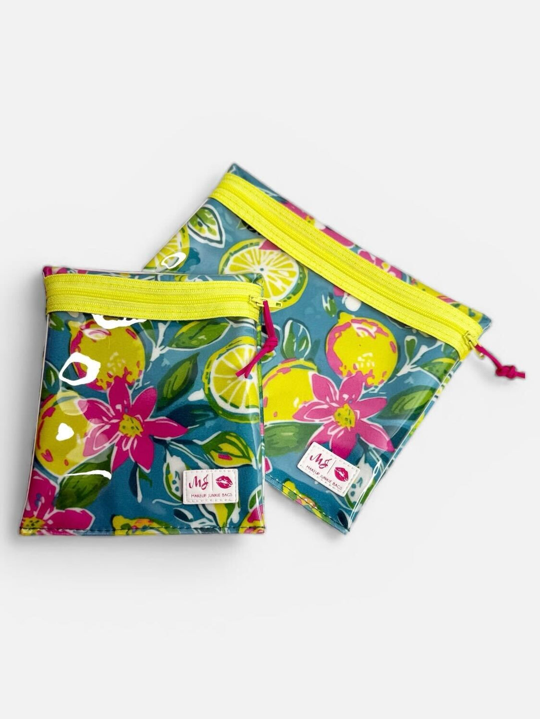 Makeup Junkie Bags set of two clear zip pouches in teal lemon and floral print with yellow zippers and pink zipper pulls on light gray background