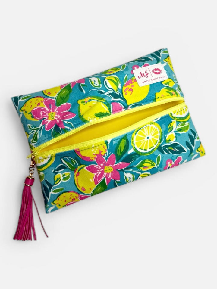 Makeup Junkie Bags large flat zip clutch in teal lemon and floral print open showing yellow interior with yellow zipper and pink tassel on light gray background