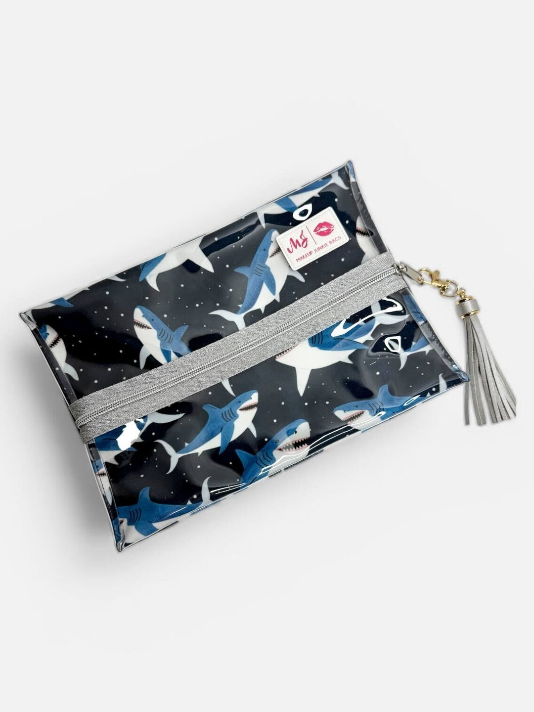 Makeup Junkie Bags large clear zip pouch in navy shark print with silver glitter zipper and silver tassel on light gray background