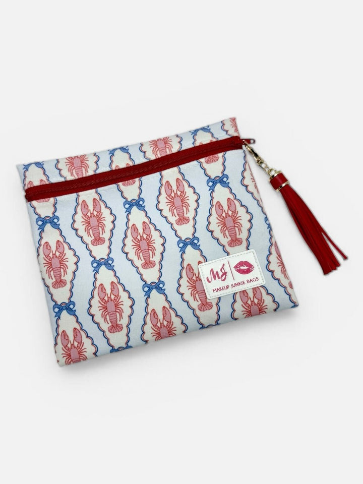 Makeup Junkie Bags medium zip pouch in pink and blue lobster print with red zipper and red tassel on white background