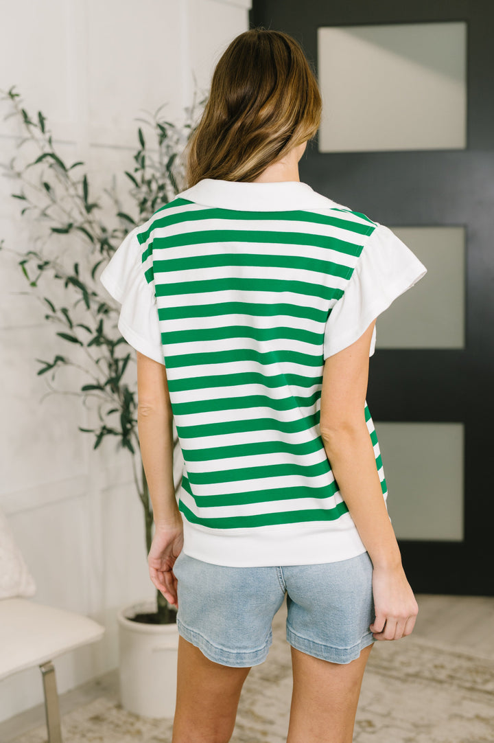 Back view — green and white striped knit polo top with flutter sleeves and denim shorts