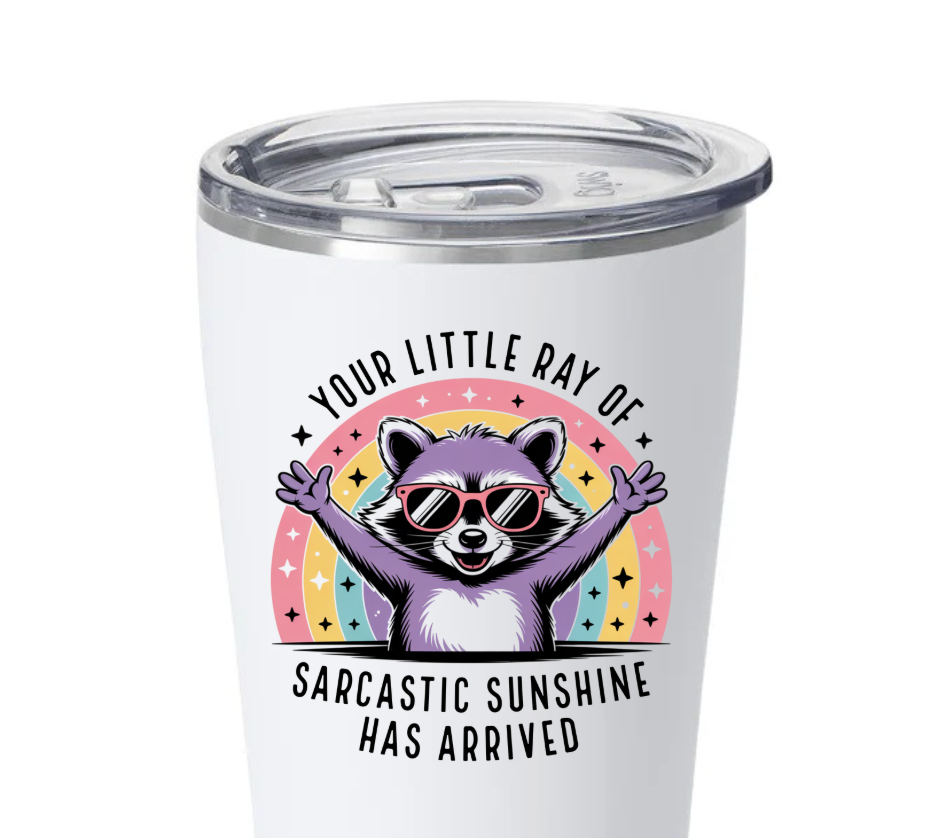 White insulated tumbler with a cartoon purple raccoon wearing pink sunglasses in front of a pastel rainbow, with the text 'Your Little Ray of Sarcastic Sunshine Has Arrived