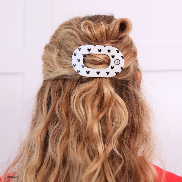 Disney x Teleties Mickey Mouse small flat round hair clip in white with allover black Mickey silhouette print securing a half-up twisted style on blonde wavy hair against white background