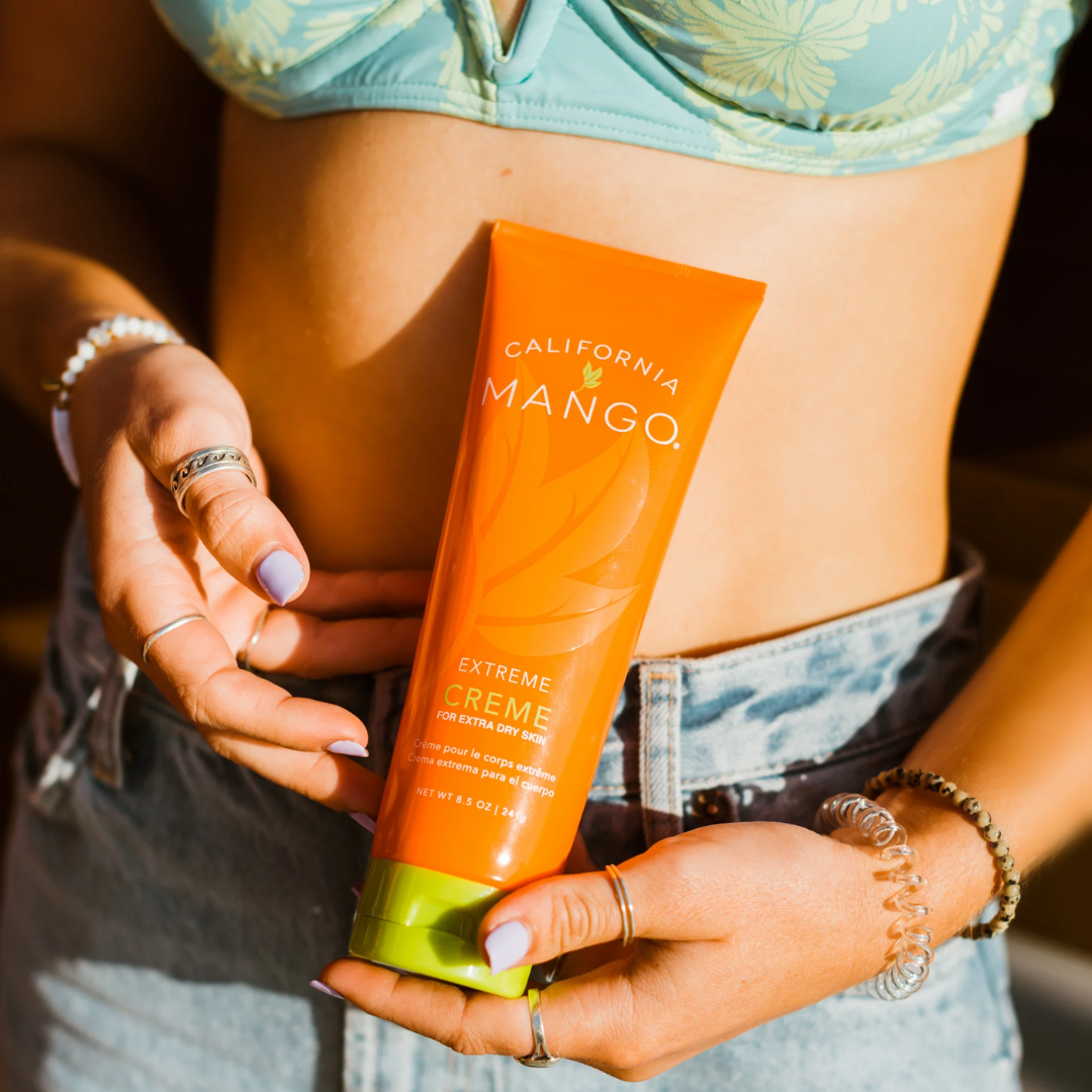 Woman holding a California Mango Extreme Creme tube for extra dry skin, 8.5 oz, lifestyle shot
