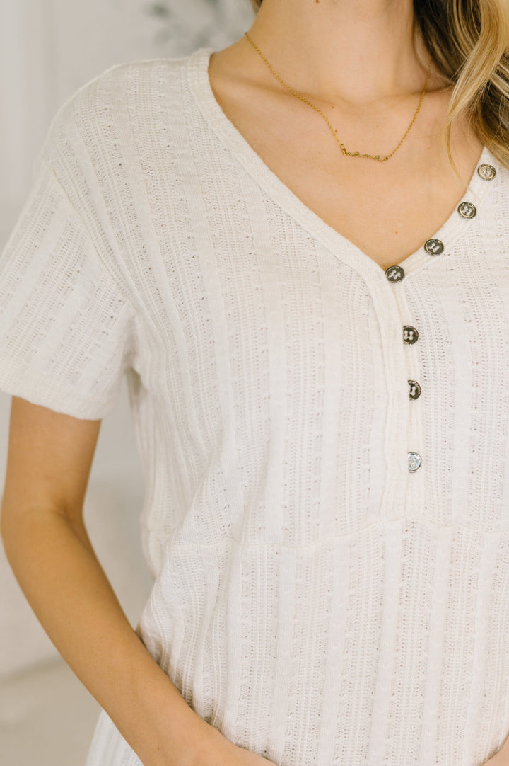 Close-up of a cream short-sleeve henley top with button placket detail