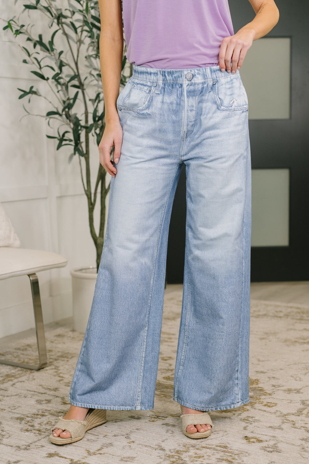 Front view — light wash wide-leg jeans with elastic paperbag waist and front pockets, paired with tan slide sandals