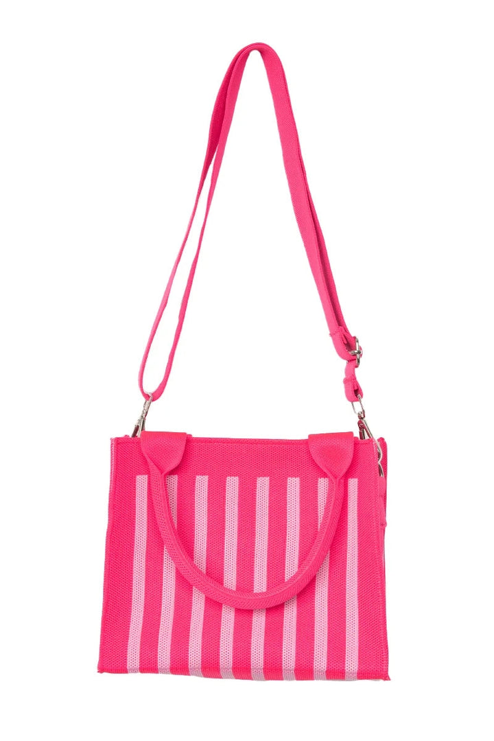 Hot pink and white stripe mesh mini tote bag worn as a crossbody with the long hot pink adjustable strap, front view.