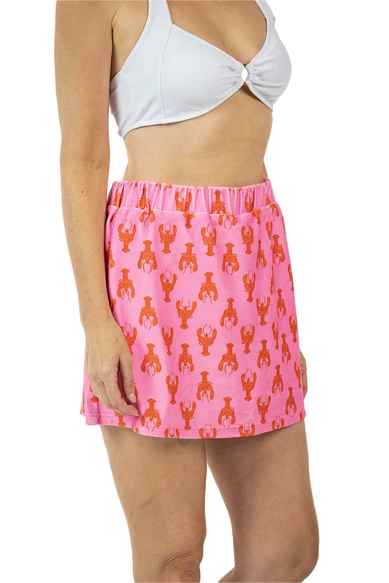 Side view of woman in a white ribbed bralette and pink lobster print elastic-waist mini skirt with red lobster motifs, on a white background.