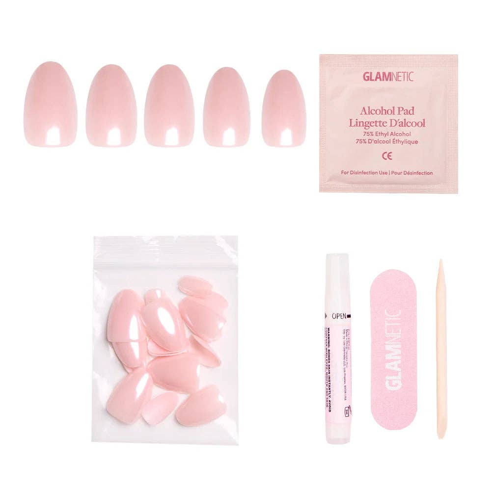 Flatlay of Glamnetic blush pink short oval press-on nail kit showing 5 nail sizes, alcohol pad, nail bag, nail glue pen, pink nail file, and cuticle stick on white background
