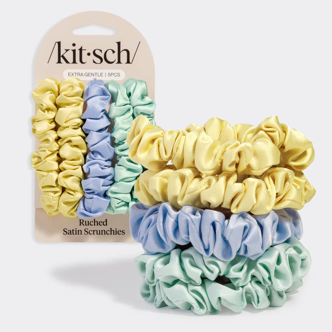 Kitsch Ruched Satin Scrunchies 5-piece set in butter yellow, periwinkle blue, and mint green, shown next to their retail packaging card labeled "Extra Gentle | 5PCS"