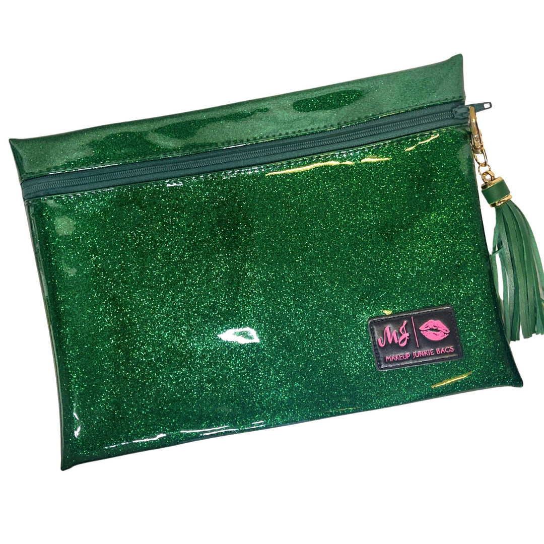 Makeup Junkie Bags emerald green glitter clear vinyl zip makeup bag with green tassel zipper pull and branded patch, front view on white background