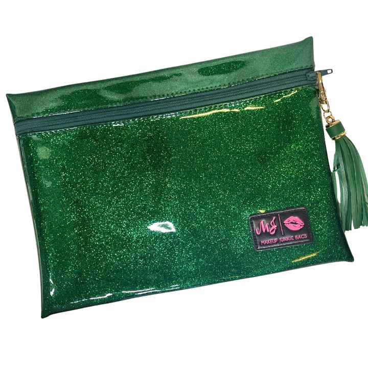 Makeup Junkie Bags emerald green glitter clear vinyl zip makeup bag with green tassel zipper pull and branded patch, front view on white background