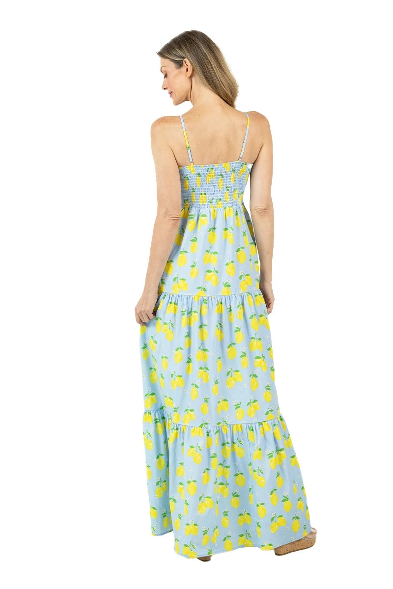 Back view of woman in a light blue lemon print smocked tiered maxi dress showing the smocked back bodice, tiered skirt, and spaghetti straps.