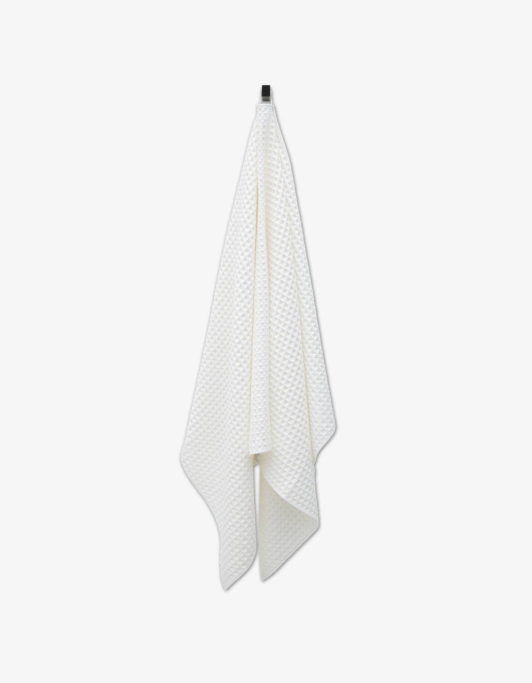 White Cloud Waffle Bath Towel by Geometry hanging on a hook against a white background