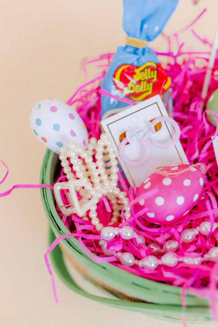 Pearl beaded bunny ear claw clip nestled in a mint green Easter basket filled with hot pink shredded paper, polka dot and striped Easter eggs, and Linny Co earring cards.