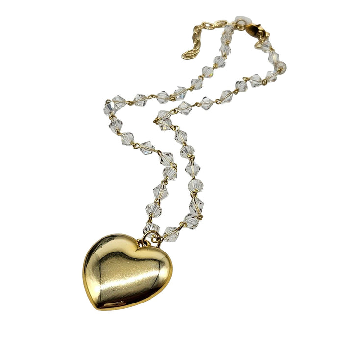 Gold heart-shaped locket on a chain with clear beads against a white background
