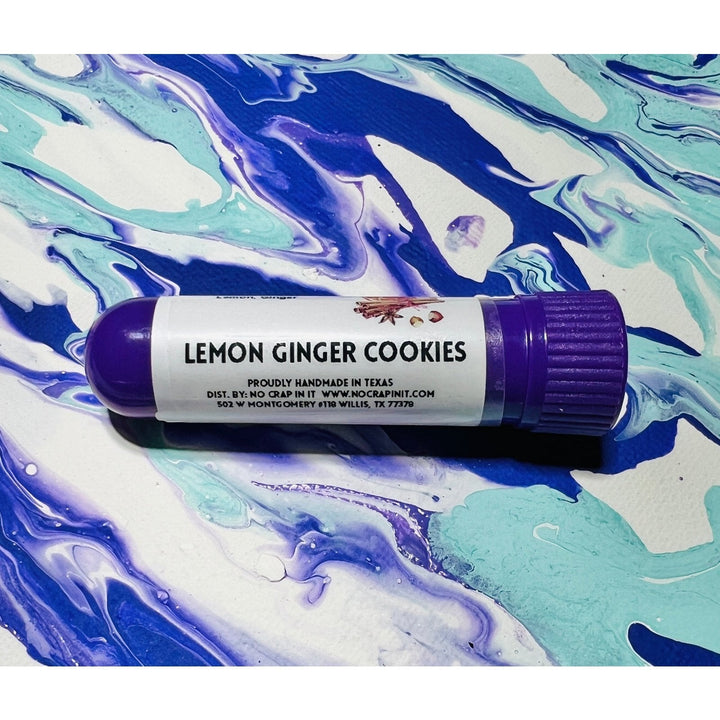 No Crap In It Lemon Ginger Cookies essential inhaler with purple cap, made with lemon and ginger, lying on a blue, purple, and white swirled paint background.