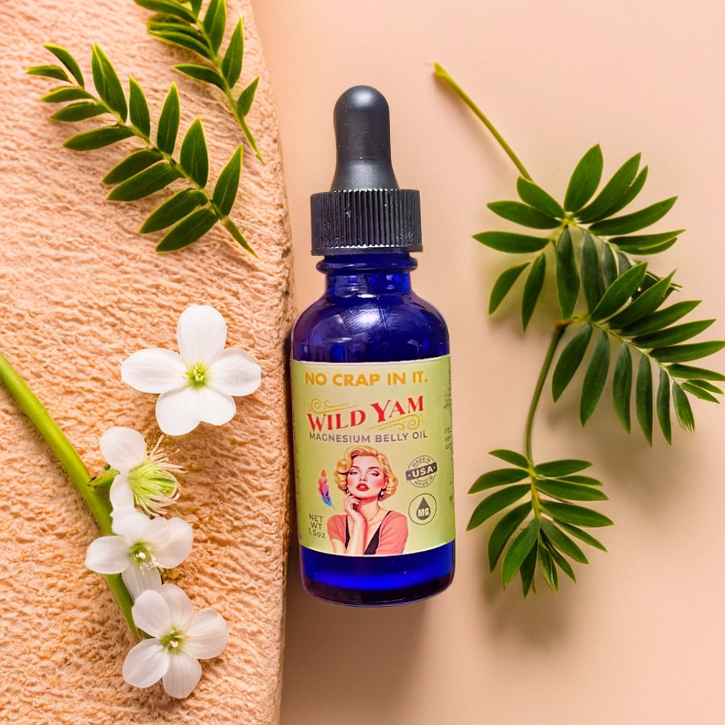 No Crap In It Wild Yam Magnesium Belly Oil 1.5 oz cobalt blue dropper bottle with vintage pin-up label, surrounded by white flowers and green leaves on peach background