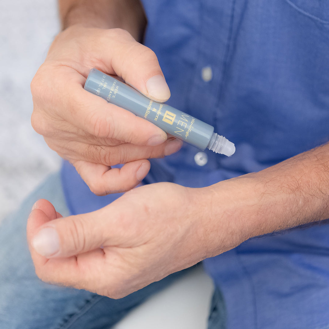 Mixologie Men's Fragrance II Modern & Masculine, 5 ml rollerball, being applied to wrist by man in blue button-down shirt