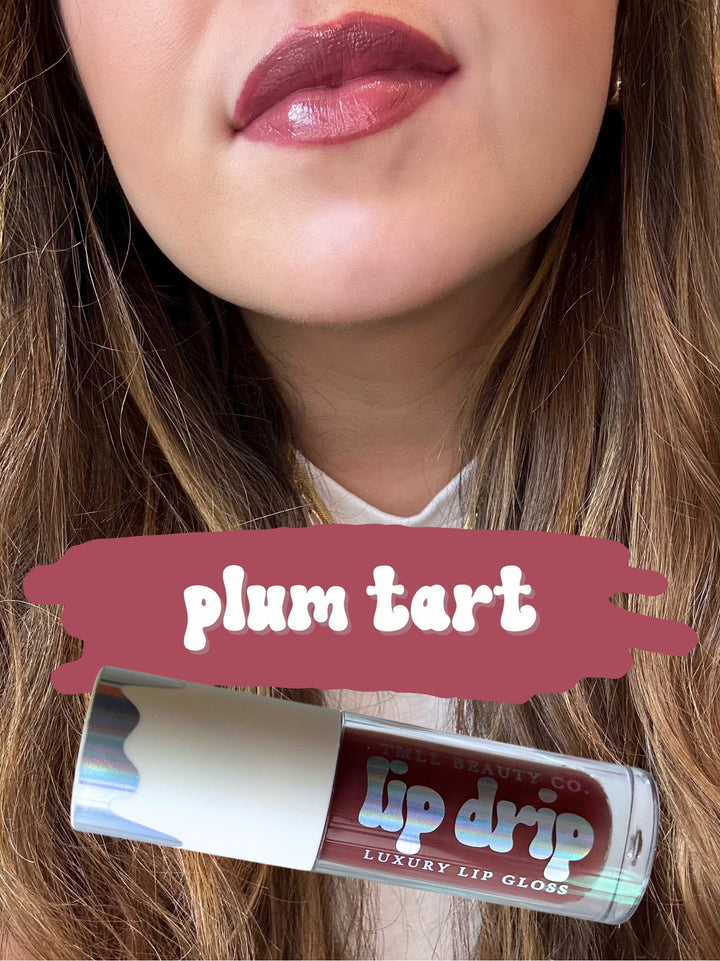 TMLL Beauty Co. Lip Drip Luxury Lip Gloss in Plum Tart — a deep mauve-plum shade shown on lips with holographic tube below