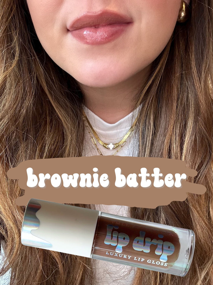 TMLL Beauty Co. Lip Drip Luxury Lip Gloss in Brownie Batter — a warm medium brown shade shown on lips with holographic tube below
