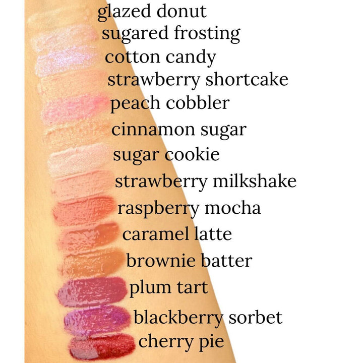 TMLL Beauty Co. Lip Drip Luxury Lip Gloss arm swatches showing all 14 shades from sheer to deep, labeled glazed donut through cherry pie