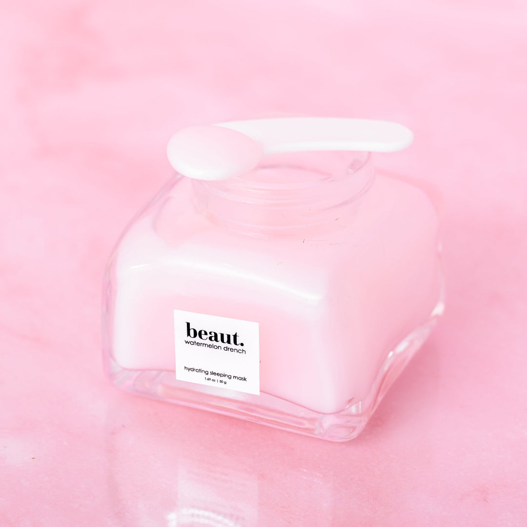 Beaut Watermelon Drench Hydrating Sleeping Mask 50g open glass jar with spatula resting on lid shot from above against pink background